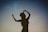 silhouette of woman holding hat in blue and gray nebula