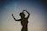 silhouette of woman holding hat in blue and gray nebula