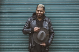 man holding black cowboy hat standing in front of roll-up door
