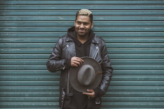 man holding black cowboy hat standing in front of roll-up door