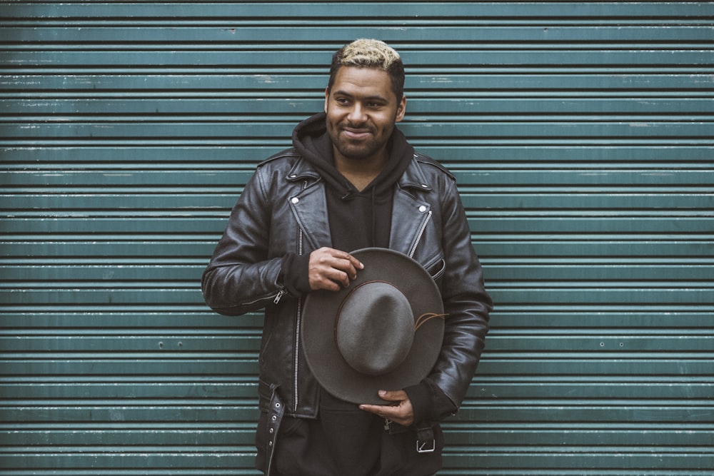 man holding black cowboy hat standing in front of roll-up door