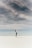 woman looking up to the sky while standing on white sand