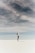 woman looking up to the sky while standing on white sand