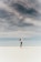 woman looking up to the sky while standing on white sand