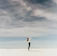 woman looking up to the sky while standing on white sand