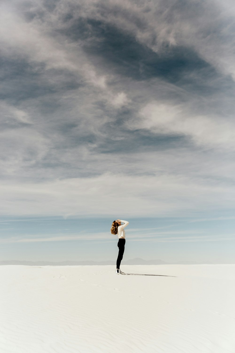 Mujer mirando hacia el cielo mientras está de pie sobre arena blanca