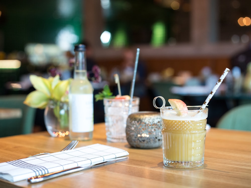 filled liquid in glass beside fork and table knife near bottle on table