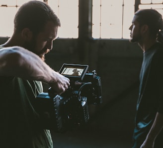 man holding camcorder with man near wall