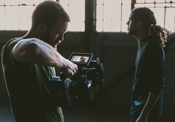 man holding camcorder with man near wall