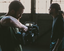 man holding camcorder with man near wall