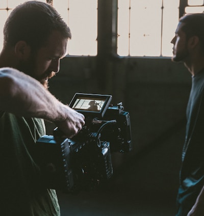 man holding camcorder with man near wall