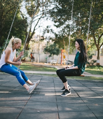 Two young women sittings on swings to demonstrate naturalistic therapy sessions