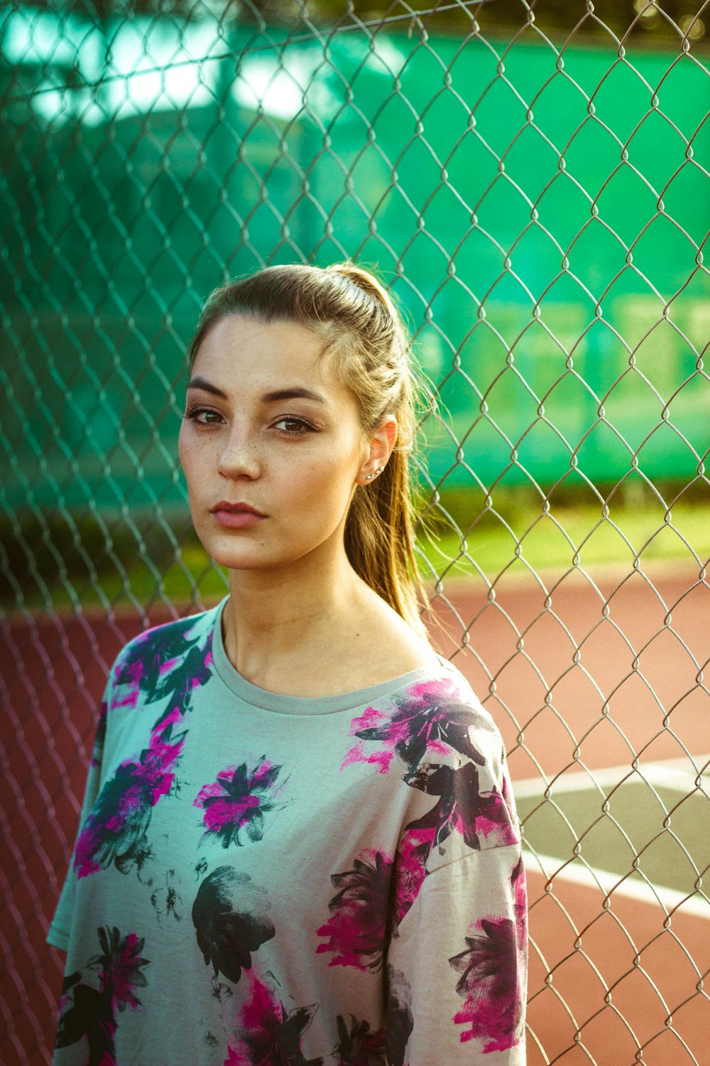 woman wearing floral top beside chain link fence during day