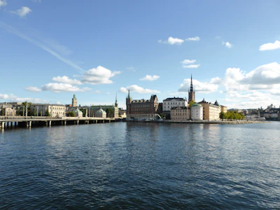 A serene view of a Great Lakes shoreline with a municipal building in the background under a clear sky.