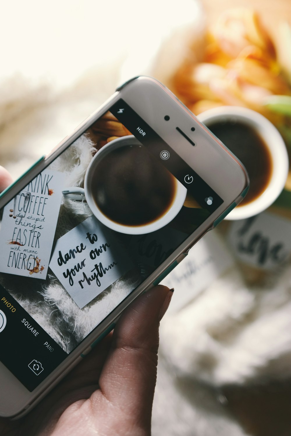 Um smartphone tirando uma foto de uma xícara de café preta.
