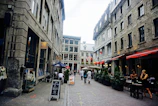 Historic cobblestone street lined with charming cafes and flowering balconies.