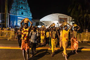A group of travelers in traditional attire participating in a ritual procession along a temple pathway.