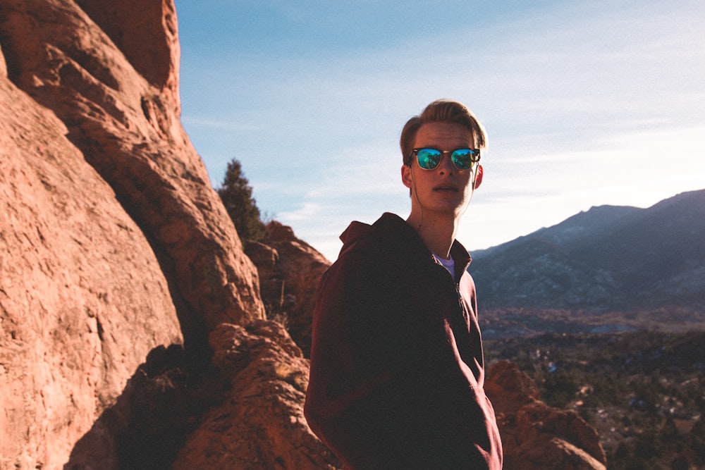 man standing beside rocking cliff