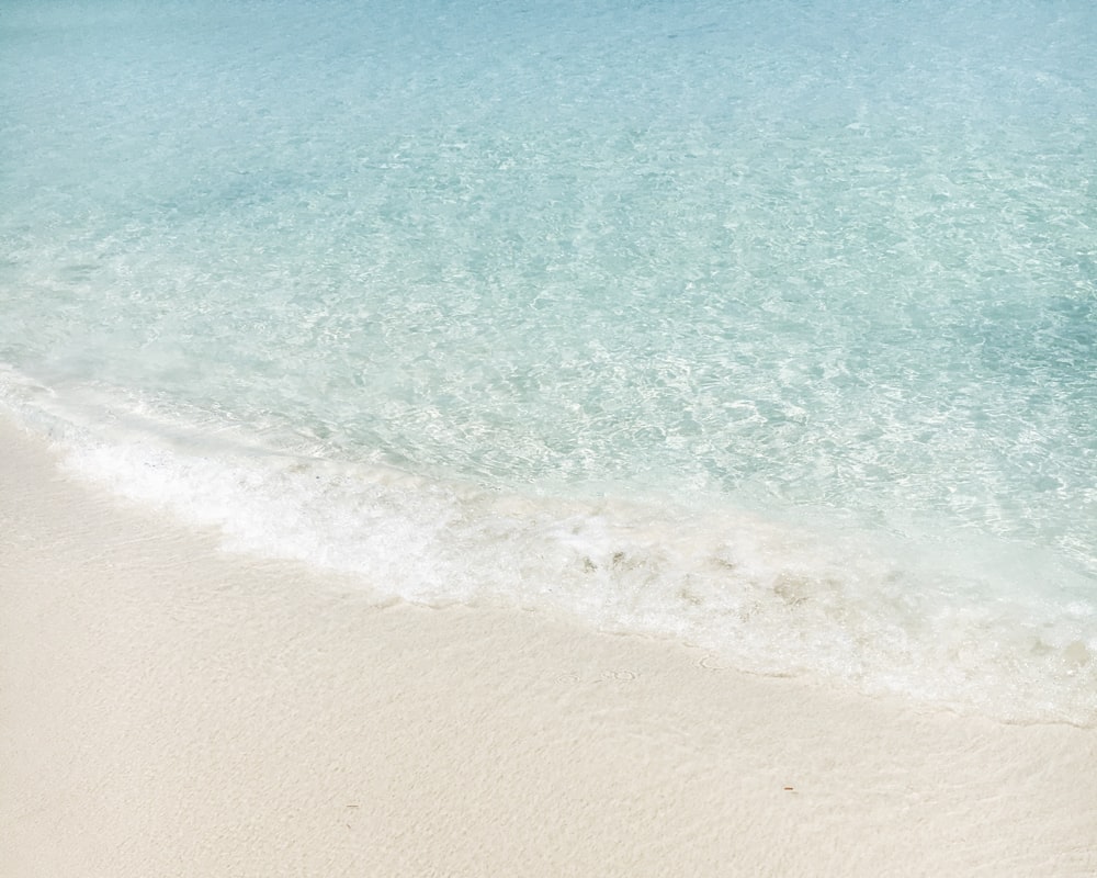 Des vagues cristallines arrivent sur une plage de sable blanc.