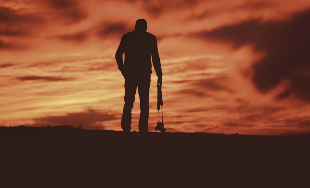 uomo in piedi che trasporta la macchina fotografica rivolta verso il campo durante il giorno