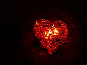 A fiery heart glowing brightly against a dark night sky during a romantic fire show.