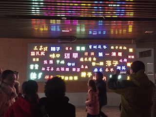 A diverse group of students learning basic Chinese characters in a bright classroom.