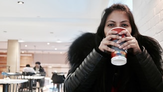 Headshot of Emma, smiling warmly with a latte in hand, set against a cozy café backdrop.