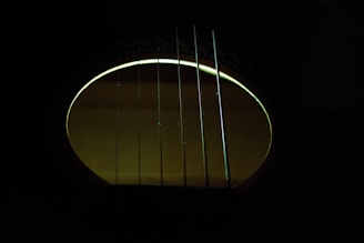 A moody close-up of ethereal guitar strings glowing under violet stage lights.