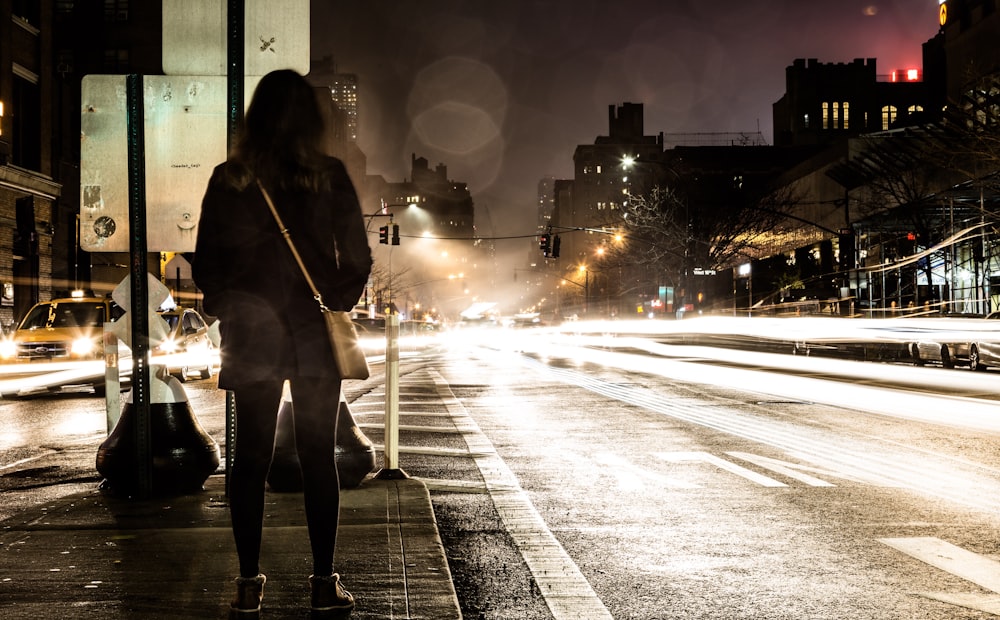 timelapse photography of woman standing near road