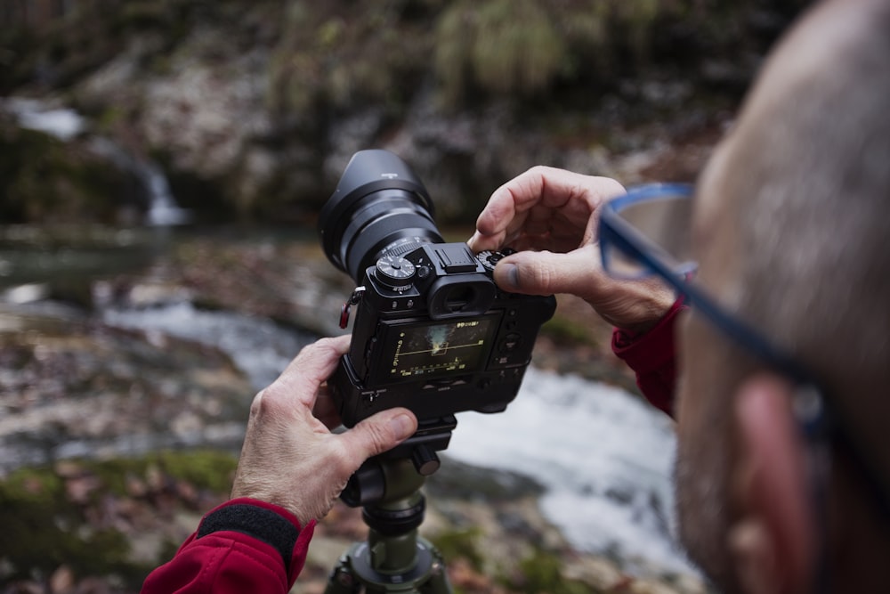 hombre tomando foto del río usando una cámara DSLR