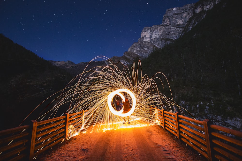 time-lapse photography of person holding steel wool on bridge