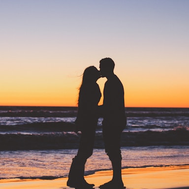 silhouette of couple sitting on seashore