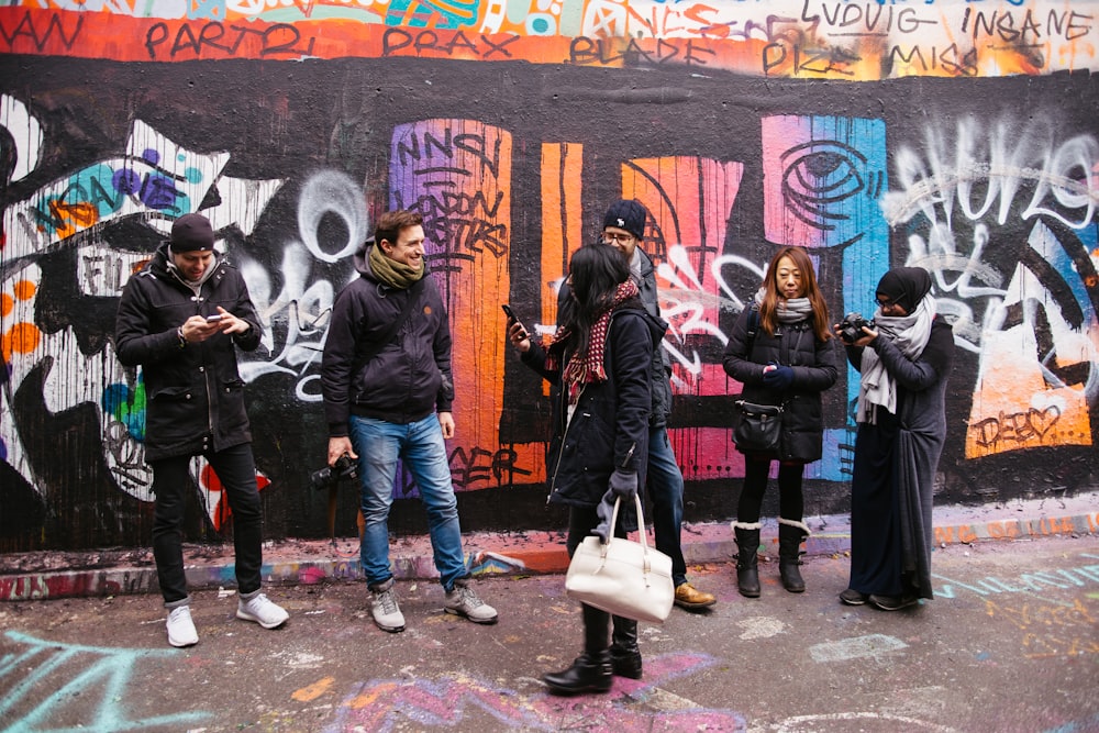 people walking beside painted wall