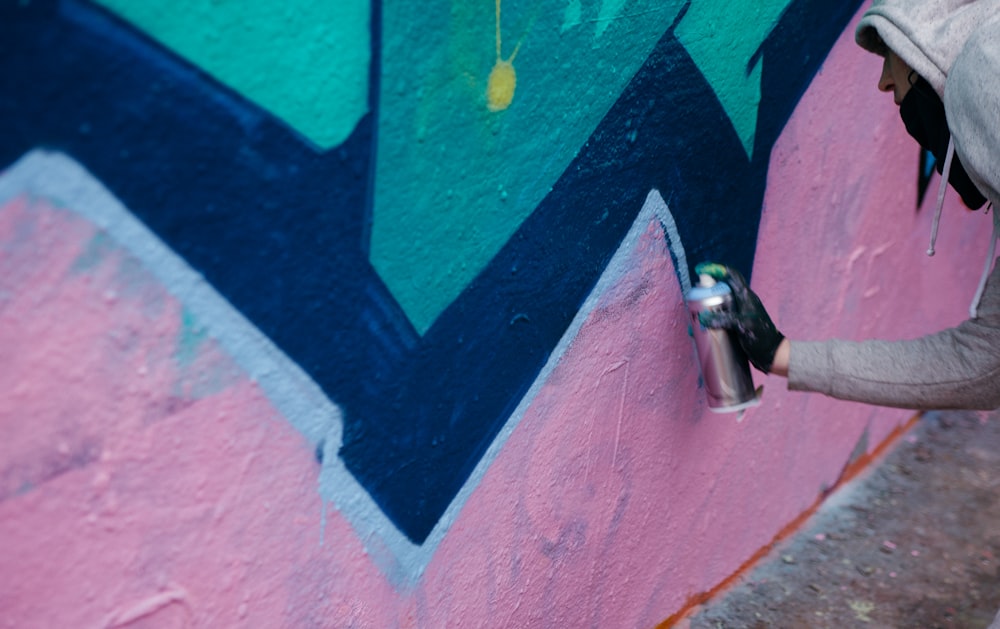 person in hoodie making a graffiti art