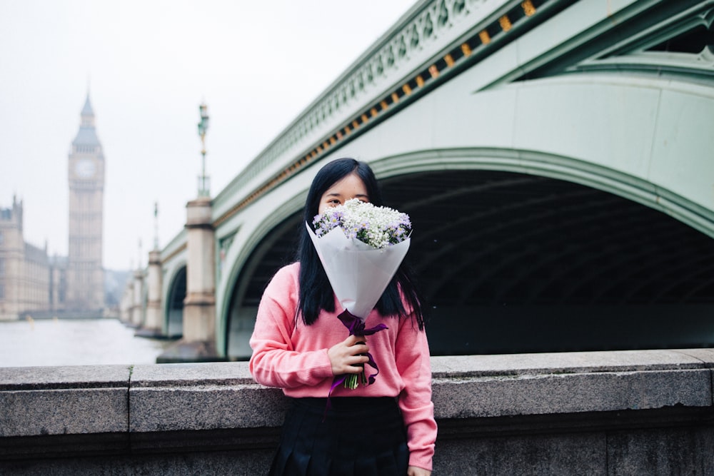 コンクリートの手すりの脇に立つ花束を持つ女性