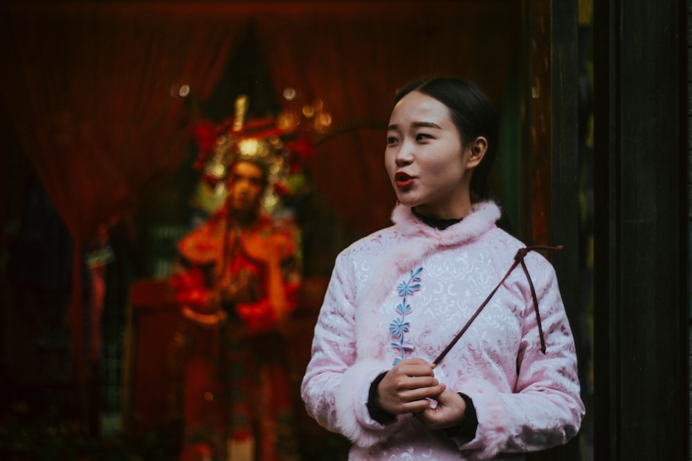 woman in pink sweatshirt holding stick shallow focus photography