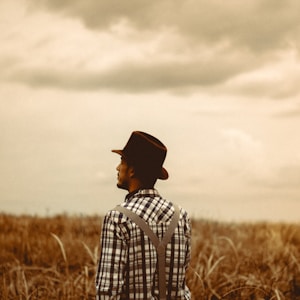 man wearing black hat standing on brown field during daytime