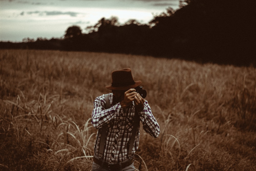 homme sur un champ d’herbe à l’aide d’un appareil photo reflex numérique