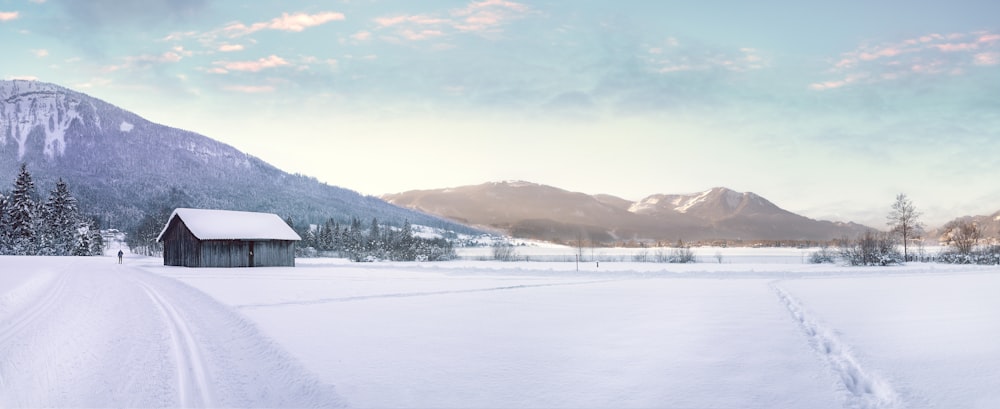 An old cottage in a snow covered field near winter alps.