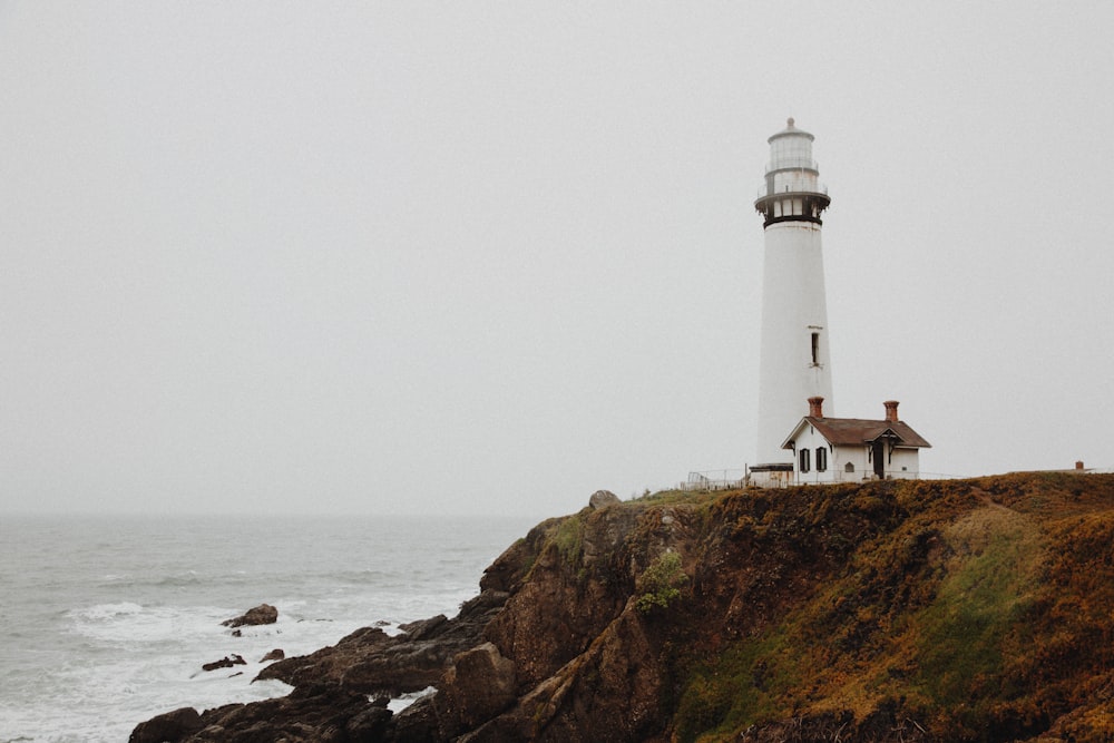 white lighthouse on rocky cliff