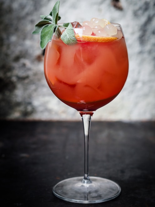 A red cocktail with a garnish