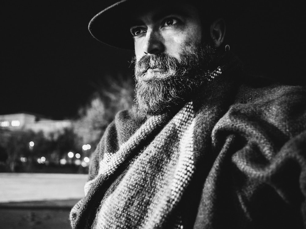 man sitting wearing cap and shawl