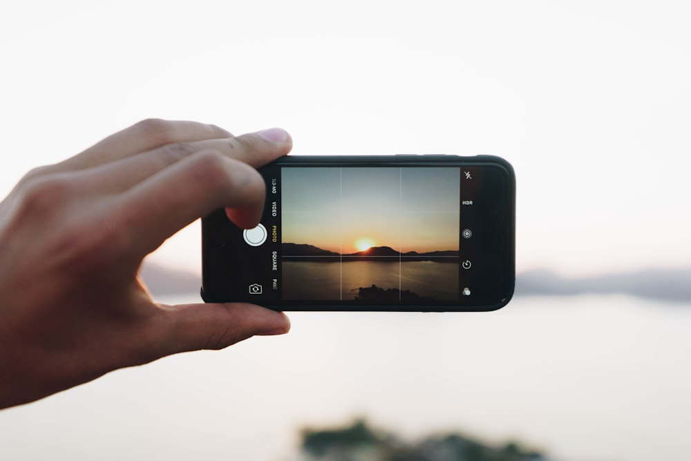 person taking picture on mountain with sun