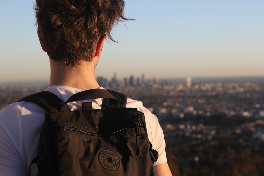 man wearing backpack on high ground