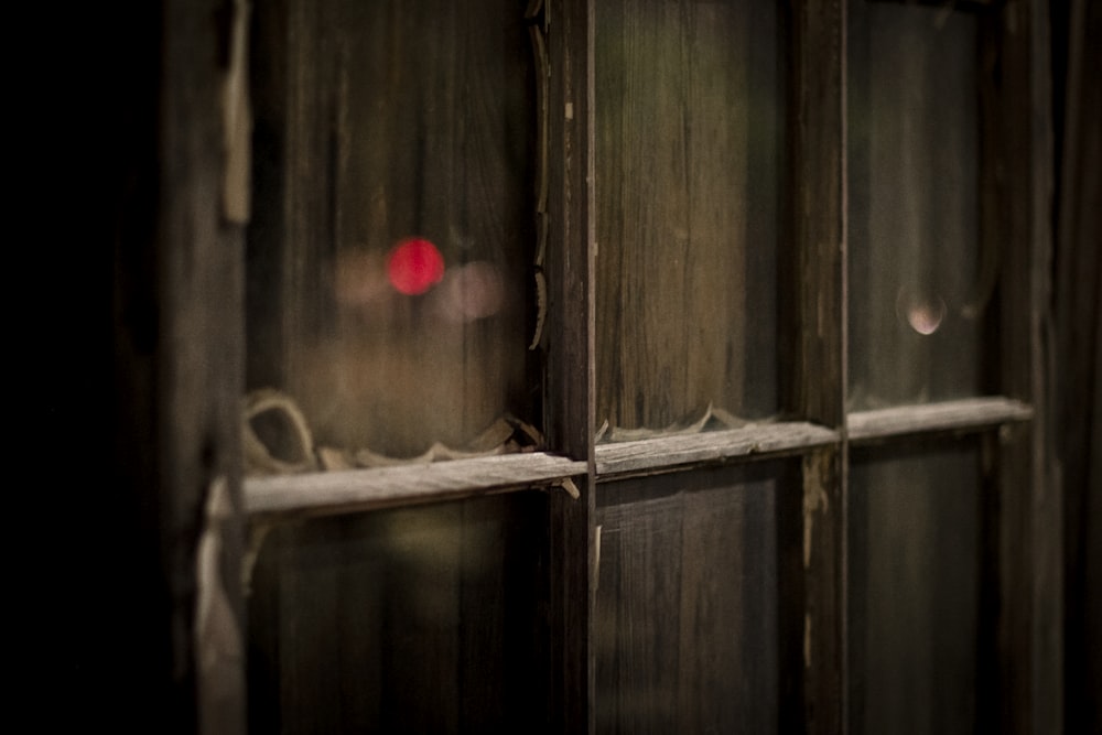 a close up of a window with a red light in the background