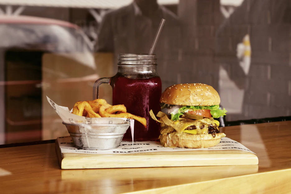 A colorful, appetizing display of a classic burger menu with crispy fries and a refreshing drink on a wooden table.