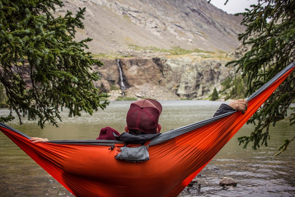 man lying on hammock beside trees