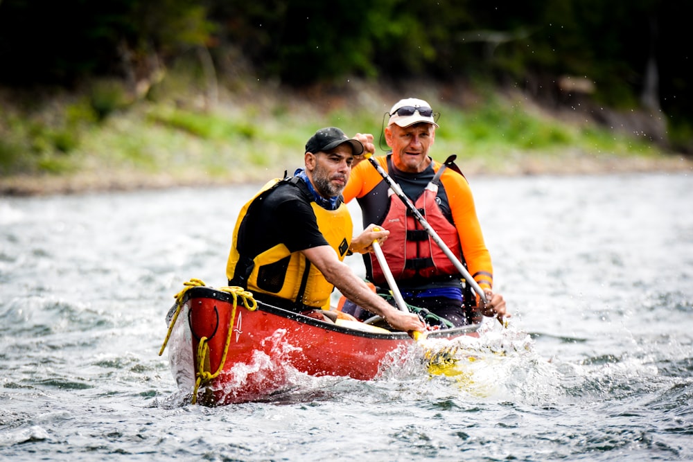 two men riding on red canoe boat