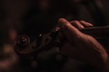 Close-up of hands gracefully playing a golden violin under soft stage lighting