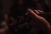Hands smoothly drawing a bow across violin strings, capturing motion and sound.